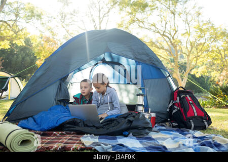 Les enfants à l'aide d'ordinateur portable dans la tente de camping Banque D'Images