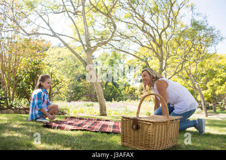 Mère et fille se propager la couverture de pique-nique dans le parc Banque D'Images