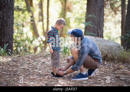 Attacher les lacets de son père lors d'une randonnée en forêt Banque D'Images