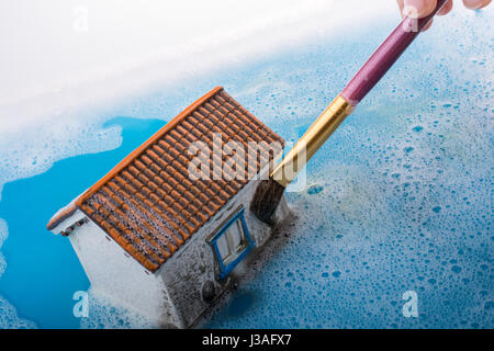 Petit modèle maison et une peinture pinceau dans l'eau mousseuse Banque D'Images