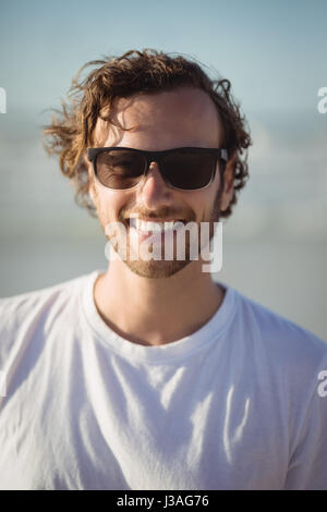 Portrait of smiling man wearing Sunglasses at plage en journée ensoleillée Banque D'Images