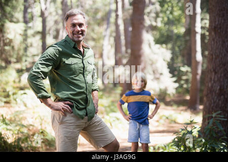 Portrait de père et fils avec les mains sur les hanches standing in forest Banque D'Images