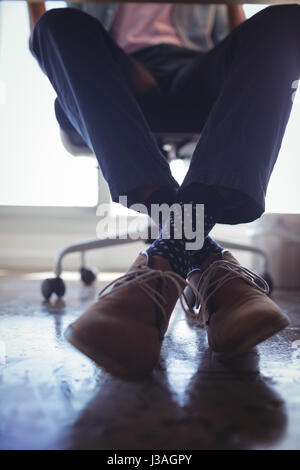 La section basse de businessman wearing chaussures brunes alors qu'il était assis sur une chaise au bureau Banque D'Images