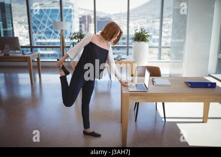 Exécutif attentif à l'aide d'ordinateur portable tout en exerçant dans office Banque D'Images
