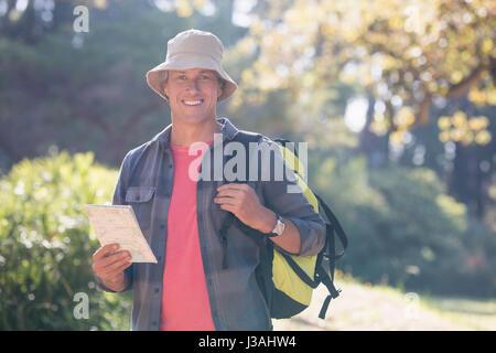 Portrait of male hiker avec map standing in forest Banque D'Images