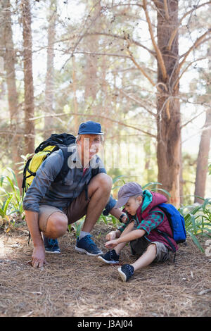 Mature père à genoux par garçon attachant lacets en forêt Banque D'Images