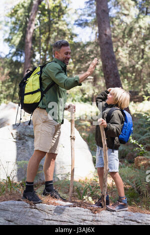 Toute la longueur de père et fils, offrant un rapport cinq lors d'une randonnée en forêt Banque D'Images