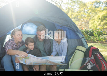 La carte de lecture en famille en tente sur une journée ensoleillée Banque D'Images