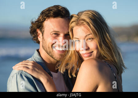 Portrait of happy couple hugging at beach au cours de journée ensoleillée Banque D'Images