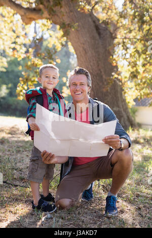 Portrait de l'heureux père et fils avec map in forest Banque D'Images