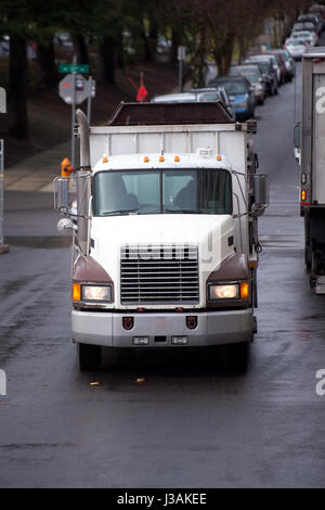 Un vieux camion semi avec un camion-benne pour le transport de matériaux de construction sur les chantiers de construction, des promenades le long de la rue de la ville avec des voitures en stationnement Banque D'Images