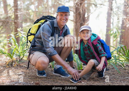 Portrait of mature père fils pour attacher les lacets sports in forest Banque D'Images