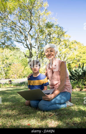 Portrait de grand-mère et petit-fils using laptop in the park Banque D'Images