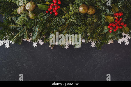 Fond de Noël avec des décorations de Noël, du vrai sapin et baie de houx des branches. Vue d'en haut, l'image aux couleurs sombres, copy space Banque D'Images