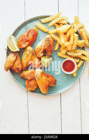 Ailes de poulet grillé avec des pommes de terre frites et des trempettes top view copy space Banque D'Images