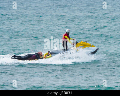 Newquay, Royaume-Uni. 4 mai, 2017. Sauvetage en mer par des sauveteurs. 4th, mai 2017. Un homme et une femme sur les planches sont sauvés de la digue par les rochers à fistral sud par un sauveteur RNLI sur un scooter à la plage de Fistral, Newquay, Cornwall, UK. Robert Taylor/Alamy Live News Banque D'Images