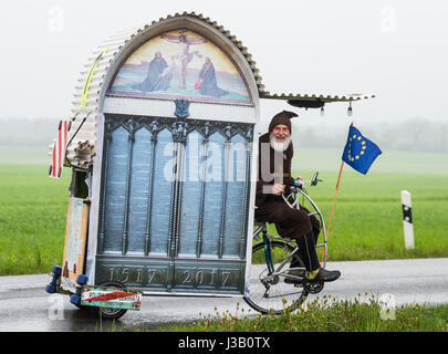 Dpatop - La location designer Dieter 'Didi' Senft les périphériques à la pluie battante avec son auto-construction 'Luther' mobile le long d'une route près de Sieversdorf, Allemagne, 4 mai 2017. Il veut prendre son vélo pour les fêtes de fin d'ouverture de l'Etat culturel année 'Millepertuis&Wirkung - Luther und die Réforme dans le Brandebourg à Francfort, de l'Oder. Senft a construit la 'Luther' Mobile pour accueillir une personne endormie. Les passionnés de cyclisme de ventilateur a travaillé sur des vélos spéciaux pendant des années, gagnant plusieurs records du monde. Il est surtout connu comme le 'Tour Devil' sur le Tour de France. Photo : Patrick Pleu Banque D'Images