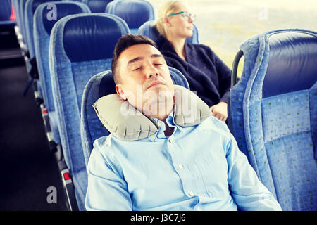 Man sleeping in billet d'autobus avec oreiller cervical Banque D'Images