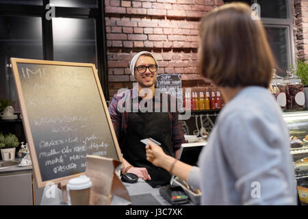 Barman et femme de payer par carte de crédit au café Banque D'Images