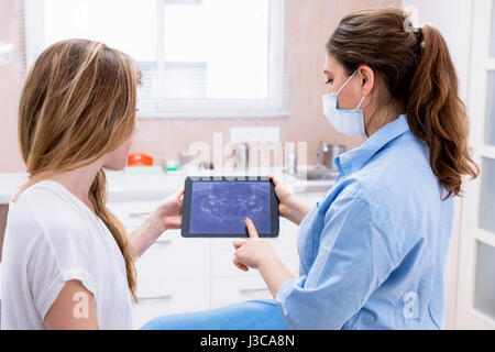 Dentist showing teeht x-ray sur tablet pc ordinateur pour femme patient au cabinet dentaire Banque D'Images