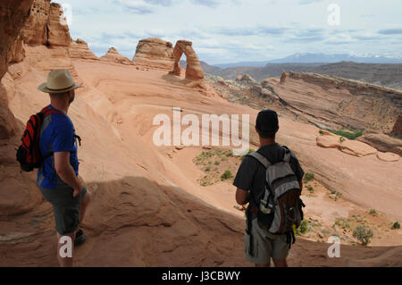 Deux randonneurs se tournent vers l'Delicate Arch dans Arches National Park, Moab, Utah. Ils sont les deux seules les personnes bénéficiant de cette vue large. Banque D'Images