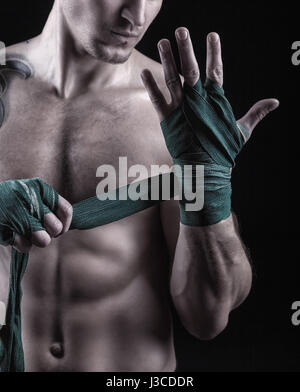 Portrait d'un boxeur de mettre sur le dos de la préparation pour le combat sur fond sombre Banque D'Images