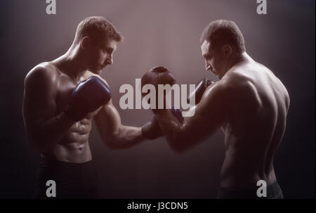 Deux boxer avec des gants de boxe avant un combat sur un fond noir Banque D'Images