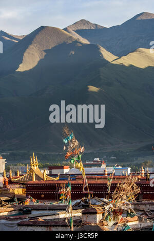 Les pinacles d'or de temple du Jokhang parmi beaucoup de toits de maisons à Lhassa et en fin d'après-midi au soleil en montagne backgroud Banque D'Images