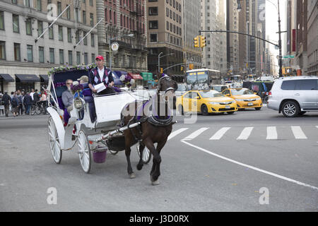 Cheval et du chariot avec les passagers traverse Central Park South et 6ème Avenued dans Central Park à Manhattan, New York City. Banque D'Images