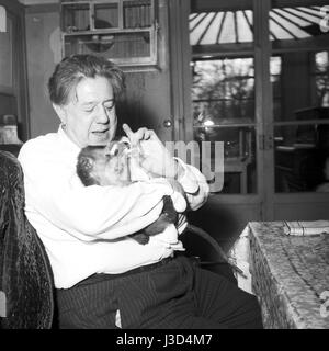 Acteur suisse Michel Simon nourrir ses monkey à Noisy-le-Grand, c.1958. Banque D'Images