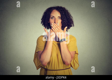 Closeup portrait jeune femme couvrant la bouche fermée avec les mains. Concept ne disent pas le mal isolé sur fond de mur gris. L'émotion expression visage s Banque D'Images