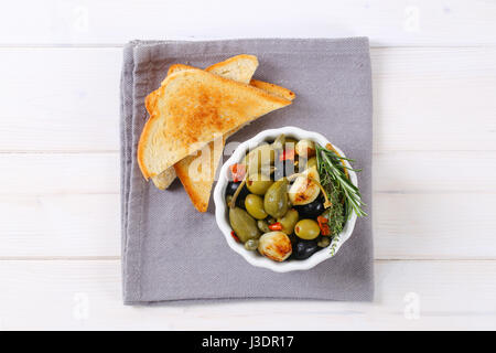 Bol d'olives, câpres au vinaigre et aux câpres petits fruits servis avec du pain grillé Banque D'Images