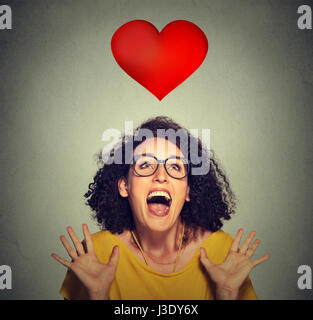 Super portrait fille funky excité dans l'amour à la recherche jusqu'à cœur rouge isolé sur fond de mur gris Banque D'Images