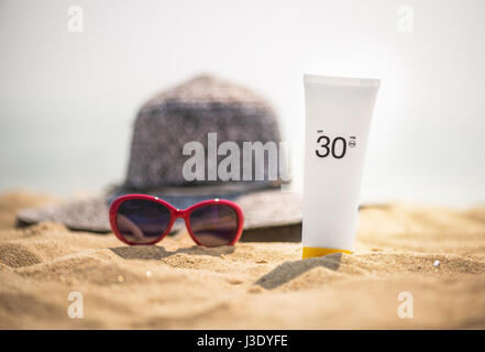 Bouteille de crème solaire sur la plage de sable Banque D'Images