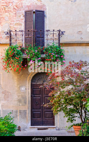 La moitié des volets fermés pendant siesta sur un balcon décoré par des fleurs à Pienza, Toscane, Italie Banque D'Images