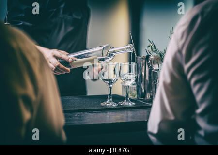 Barman de servir de l'alcool des boissons derrière comptoir bar. Banque D'Images