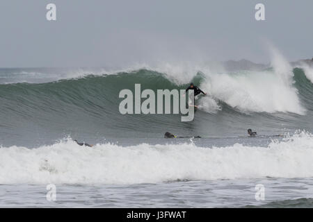 Surfer en combinaison noire attraper une vague dans la plage de Zurriola (San Sebastian, Espagne). Banque D'Images