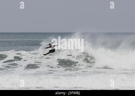 Surfer avec une extrême pose, attraper une vague dans la plage de Zurriola à San Sebastian (Guipuzcoa, Espagne) 2017. Banque D'Images