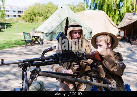 Salute to the 40s re-enactment. Enfant, garçon blond, 6-7 ans, en uniforme de l'armée britannique, étant montré comment fire la mitrailleuse Bren par Desert Rat soldat. Banque D'Images