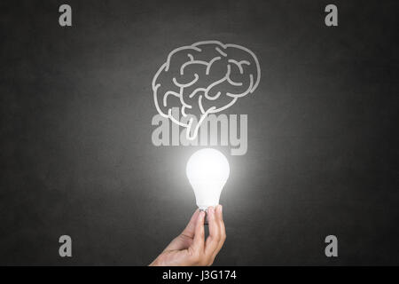 Hand holding Light bulb on blackboard Banque D'Images