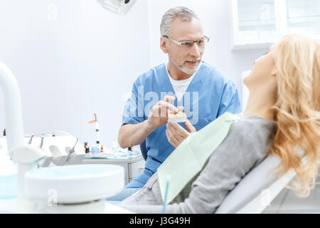 Dentist showing patient modèle à mâchoires dans une clinique dentaire Banque D'Images