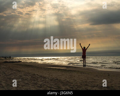 Happy boy sur la plage au coucher du soleil Banque D'Images