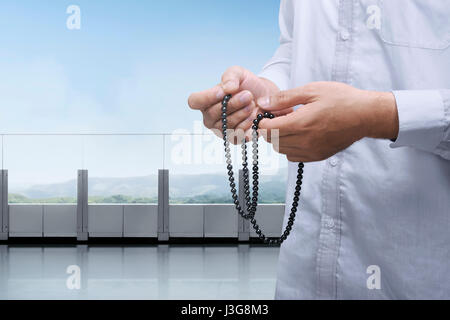 Les mains des musulmans en prière avec le chapelet dans le balcon à l'arrière-plan de la vue du paysage Banque D'Images