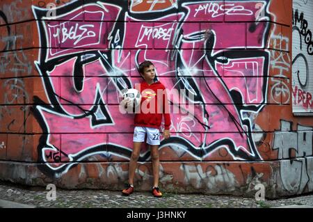 Stock Photo - Berlin, Allemagne. Jeune garçon joue au football sur un coin de rue avec graffiti en tant que crédit : Paul Velasco/ Alamy Banque D'Images