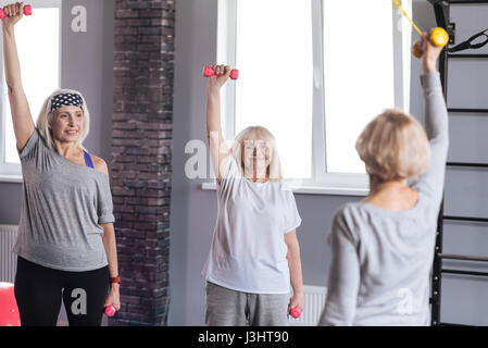 La levée de poids. Nice joyeuse de femme debout dans le cercle et holding dumbbells tout en le portant Banque D'Images