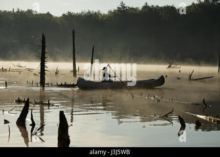 Silhouette d'une fille de canots sur un étang de castors dans le Vermont, aux États-Unis, comme le soleil se lève à travers la brume Banque D'Images