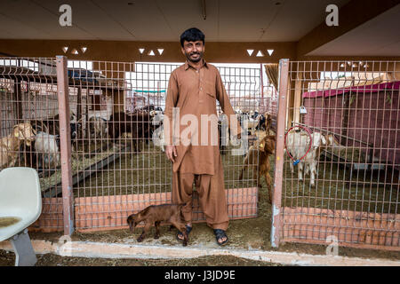 Un agriculteur pose pour une photo avec un jeune enfant dans un stylo de chèvre à l'Al Ain marché aux chameaux à Abu Dhabi, EAU. Banque D'Images