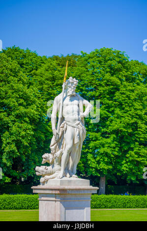 Nymphenburg, Allemagne - 30 juillet 2015 : Neptun sculpture, roi de la mer, belle journée ensoleillée, herbe verte et arbustes dans les jardins du palais. Banque D'Images