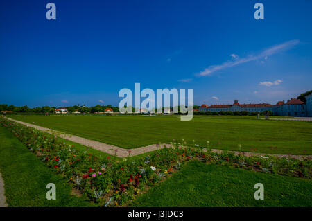 Nymphenburg, Allemagne - 30 juillet 2015 : très grand champ d'herbe avec bain de soleil, quelques bâtiments en arrière-plan, les jardins du palais. Banque D'Images