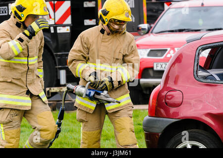 Firecrew de l'Irlande du Nord Service d'incendie et de sauvetage de démontrer comment utiliser l'équipement de coupe hydraulique pour libérer un conducteur qui était coincé dans une voiture après un Banque D'Images